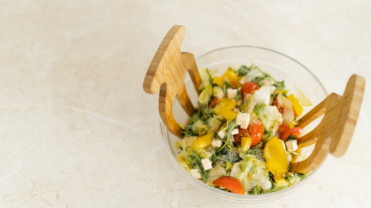 Refreshing vegetable salad with cherry tomatoes, bell peppers, and feta cheese in a clear glass bowl.